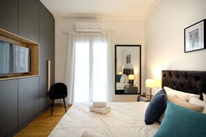 Une chambre d’hôtel équipée d’un lit, d’une télévision, d’une chaise, d’un miroir et d’un appareil de climatisation.