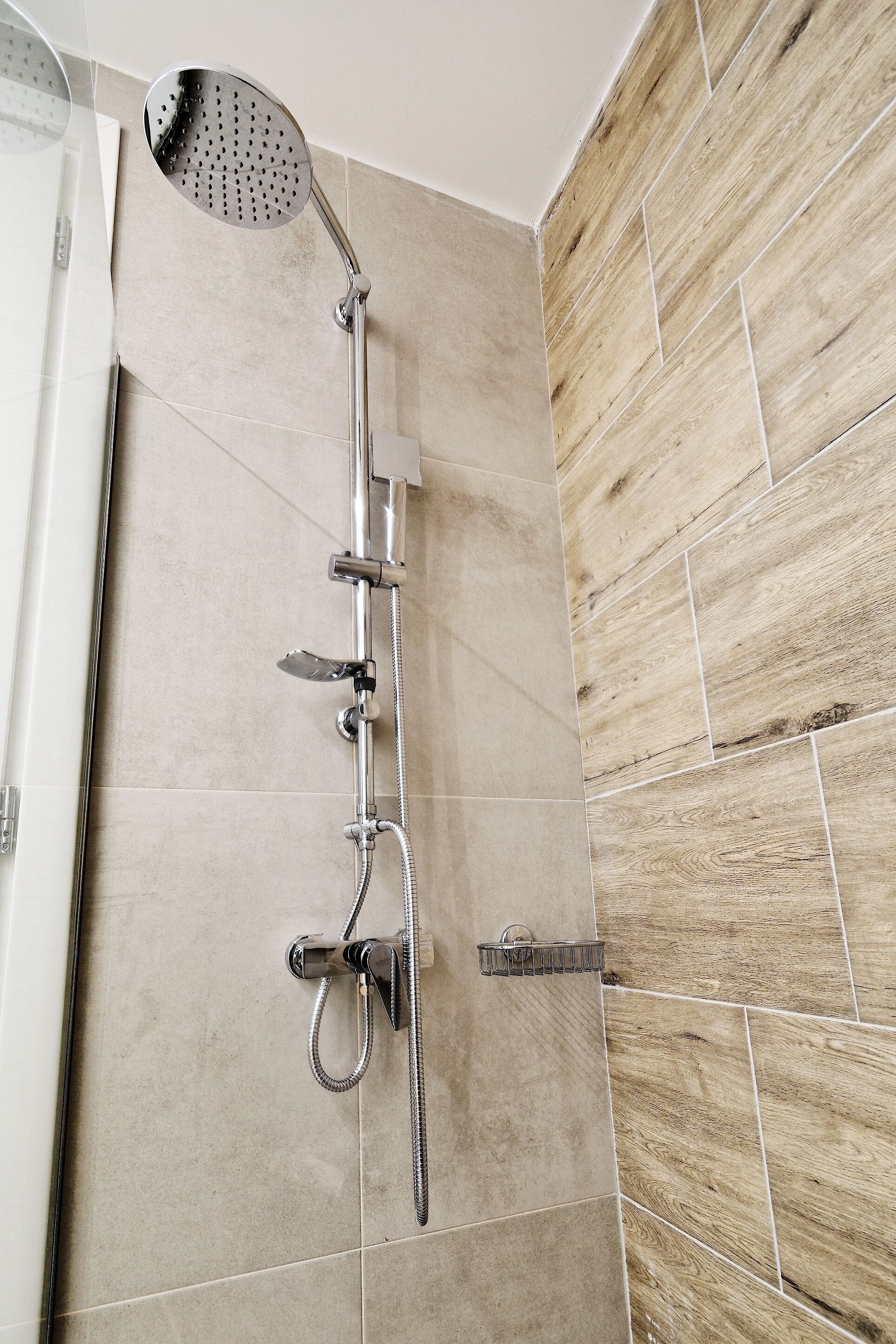 Een douche met een handdouche en een kraan die aan de muur bevestigd is.