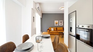 Ett modernt kök med en inbyggd ugn och en matplats med ett vitt bord och bruna stolar.