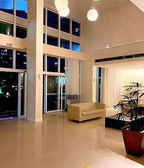A spacious interior with a high ceiling, large windows, and a modern sofa.