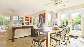 A spacious dining area with a wooden table and chairs, a sofa, and artwork on the walls.
