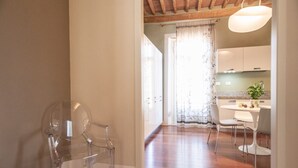 A spacious room with wooden flooring, a dining area with a table and chairs, and a kitchen visible through an open doorway. - Casa della Luce Luxury in Center Town (Lucca)