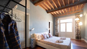 A bedroom with a bed, wooden flooring, a hanging coat rack, and a door. - Casa della Luce Luxury in Center Town (Lucca)