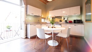 A modern kitchen with white cabinets, a round dining table, and white chairs. - Casa della Luce Luxury in Center Town (Lucca)