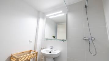 Ein modernes Badezimmer mit Holzregal, Waschbecken, Spiegel und Dusche.