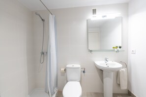 A modern bathroom with a shower, toilet, sink, and mirror.