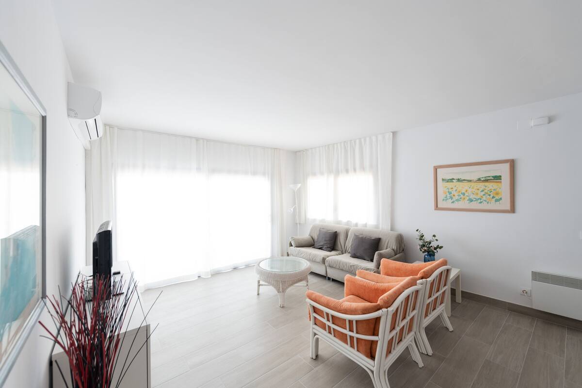 Uma sala de estar moderna com um sofá, poltronas, uma mesa de centro e uma televisão.