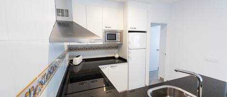 A modern kitchen with white cabinets, a stainless steel sink, a microwave, and a toaster.