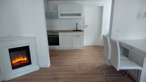 Eine moderne Küche mit weißen Schränken, einem eingebauten Backofen und einem Kamin.