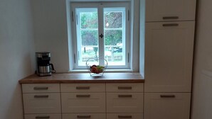 Eine Küche mit Fenster, einer Kaffeemaschine und einer Obstschale auf der Arbeitsfläche.