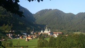 Eine Stadt mit einem markanten Kirchengebäude, umgeben von grünen Hügeln und blauem Himmel.
