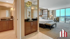 A modern hotel room with a large bed, a separate seating area, a kitchenette, and a balcony with a view. - Tower 3 Studio | Strip View, Jacuzzi & Pool (Las Vegas)