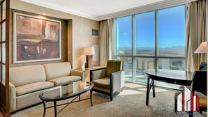 A hotel room with a large window, a sofa, a chair, a table, and a painting on the wall. - Tower 3 Studio | Strip View, Jacuzzi & Pool (Las Vegas)