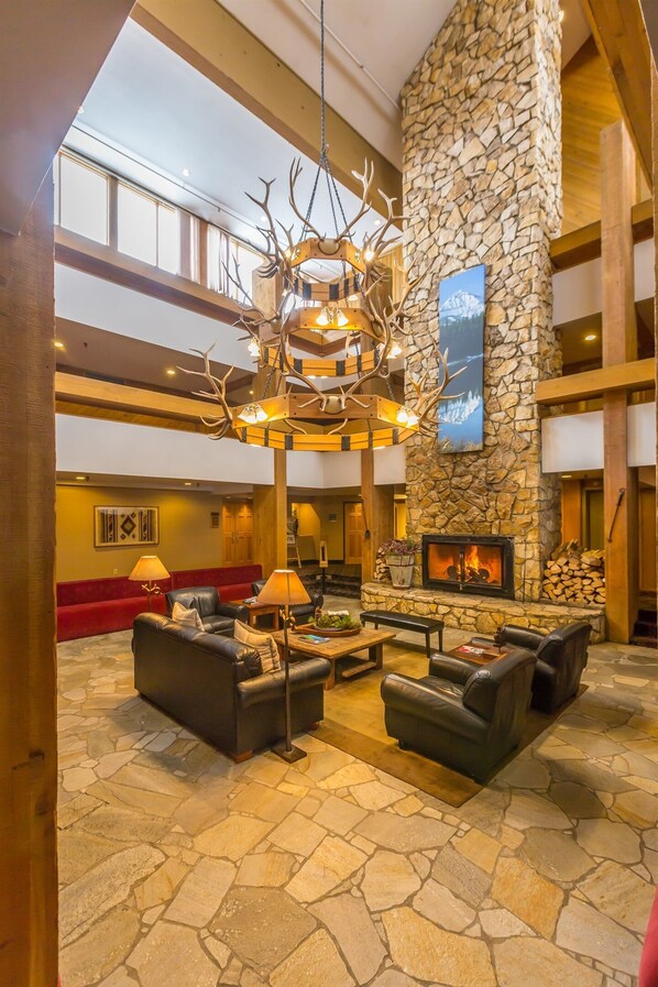 A spacious lobby with a stone fireplace, leather seating, and a chandelier with antlers.