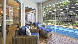 Un espace aménagé au bord de la piscine, avec des meubles en osier et une vue sur la piscine.