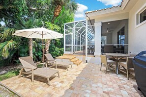 An outdoor patio with wicker furniture, a table, and a grill.