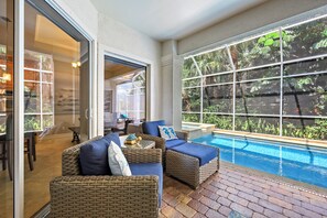 A poolside area with wicker furniture and a view of the pool.