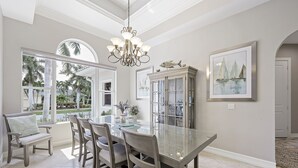 Un coin repas avec une table en verre, des chaises et un lustre.
