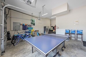 A ping pong table in a room with bicycles, a projector, and a whiteboard.