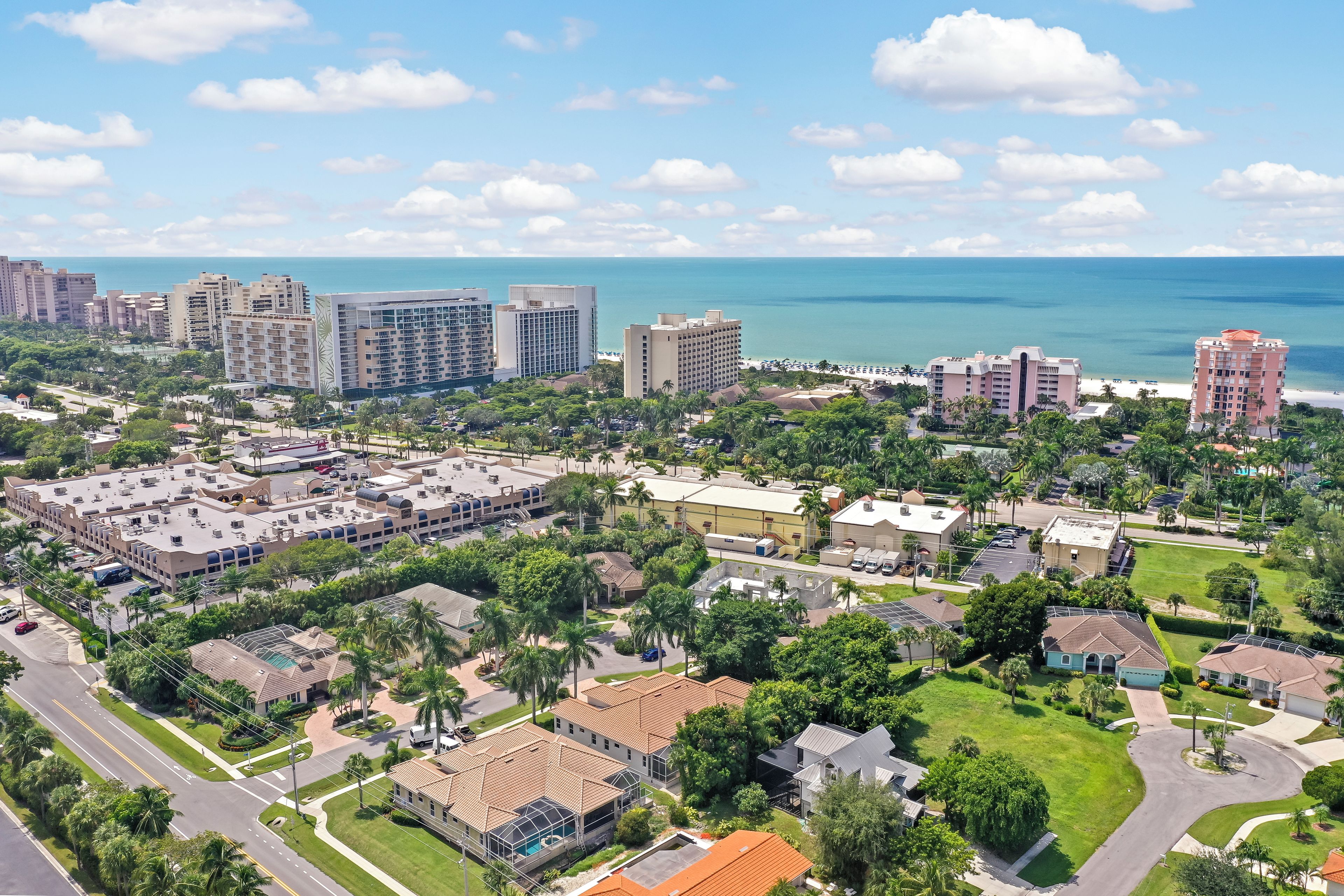Vue aérienne d’un quartier résidentiel situé sur la côte, avec ses bâtiments, ses routes et sa végétation.