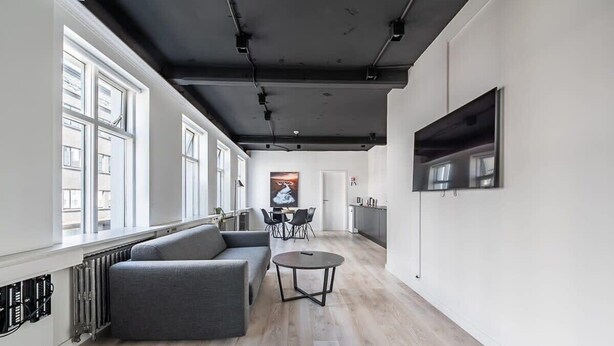 A modern living room with a grey sofa, a round coffee table, and a TV mounted on the wall.