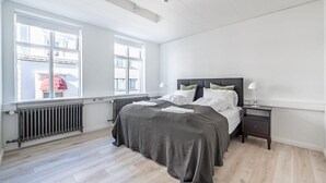 A bedroom with a bed, bedside tables, and a window.
