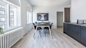 Une cuisine moderne avec un coin repas, dotée d’une grande fenêtre, d’un îlot central et d’une palette de couleurs en noir et blanc.
