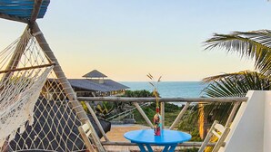 Una terrazza con un tavolo e sedie blu, un'amaca e vista sull'oceano.