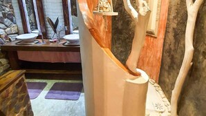 Un bagno con un design originale a forma di albero, che include un'amaca sospesa e un lavandino integrato nella struttura.