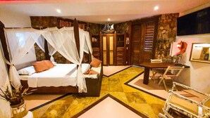 Una camera da letto con un letto a baldacchino, una scrivania con una sedia e un muro in pietra.