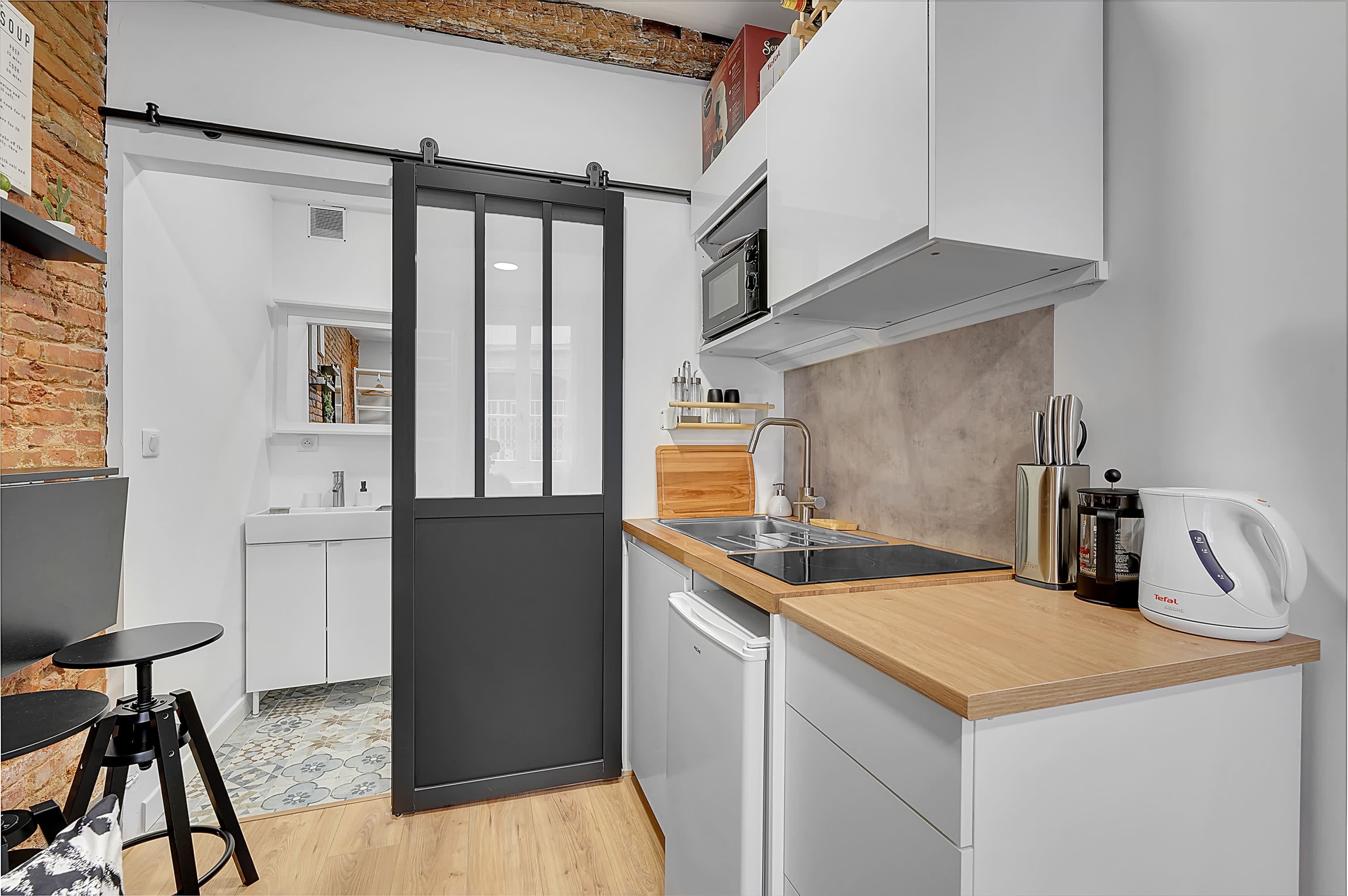 A compact kitchen with a sliding door, a microwave, a toaster, and a sink.