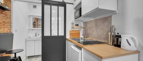 A compact kitchen with a sliding door, a microwave, a toaster, and a sink.