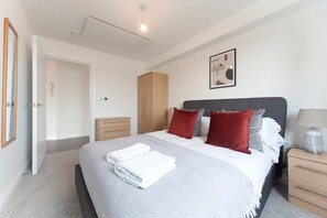 Un dormitorio moderno con cama, mesitas de noche, un armario y una obra de arte en la pared.