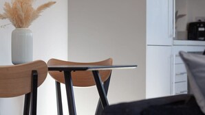 Een moderne keuken met witte kasten, een zwart aanrecht en een witte vaas met gedroogde bloemen links.