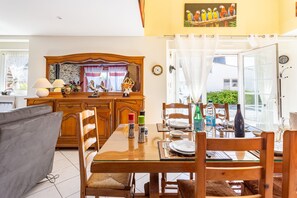 Comedor con mesa de madera, sillas y vistas al exterior a través de un ventanal.