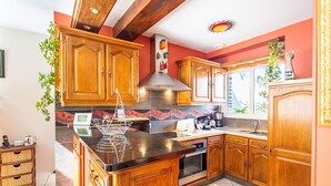 A kitchen with wooden cabinets, a black countertop, and a stainless steel range hood.