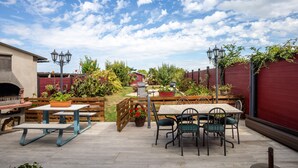 An outdoor patio with a barbecue grill, picnic table, and chairs.
