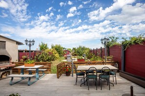 Enjoy al fresco dining on the patio, surrounded by lush greenery and a brick oven for outdoor cooking.