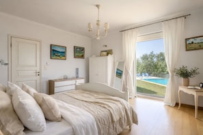 A bedroom with a bed, a dresser, a mirror, and a view of a swimming pool.