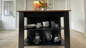 Un'isola cucina con una macchina da caffè, un frullatore e un'orchidea in vaso.