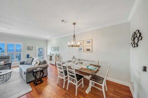 A spacious living room with a dining area, hardwood floors, and a large window offering a view. - Large Laguna Beach Home Across from Beach w/Ground Floor Suite, FREE Perks! (Panama City Beach)