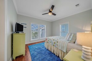 A bedroom with a bed, a television on a stand, a ceiling fan, and two windows with blinds. - Large Laguna Beach Home Across from Beach w/Ground Floor Suite, FREE Perks! (Panama City Beach)