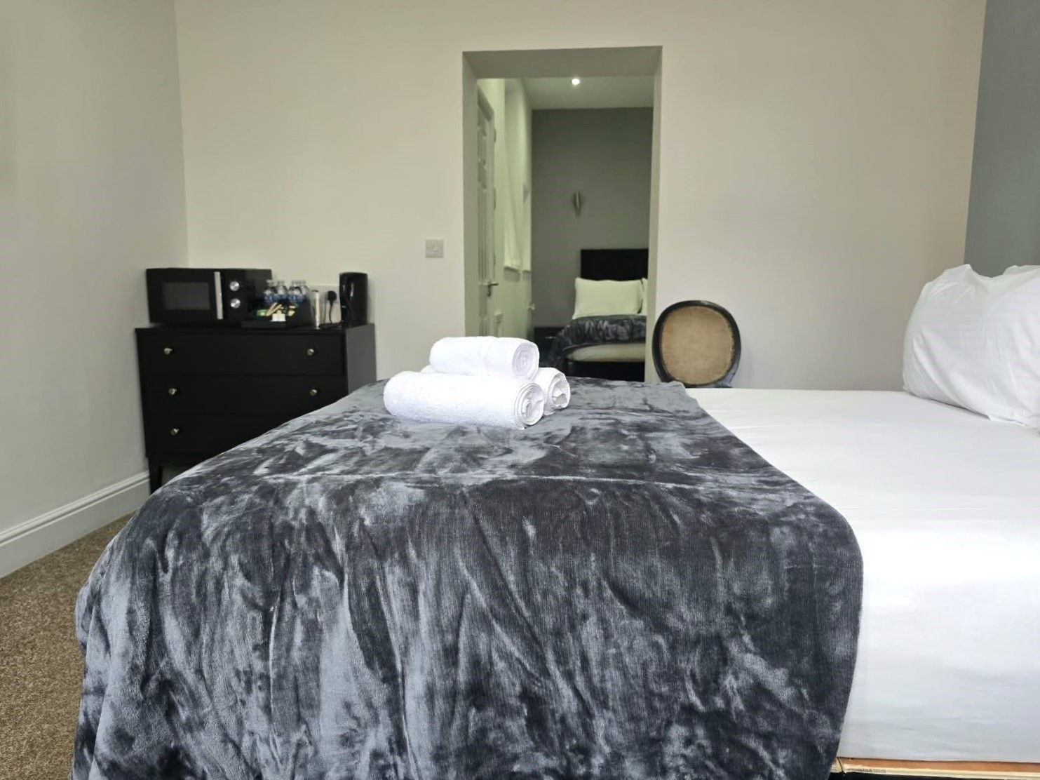 Una habitación de hotel con una cama, un aparador, un microondas y una toalla sobre la cama.