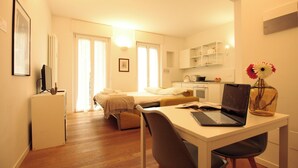 A compact hotel room with a bed, a desk with a laptop, a chair, a small kitchenette, and a bathroom. - Italianway Easy - Caterina da Forlì 6 (Milan)