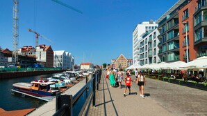 A waterfront promenade with boats docked, a pedestrian walkway, and buildings with balconies. - Elite Apartments Waterlane SPA (Gdansk)