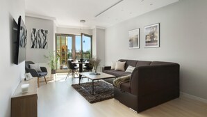 A modern living room with a sofa, coffee table, and a dining area with chairs and a table. - Elite Apartments Waterlane SPA (Gdansk)