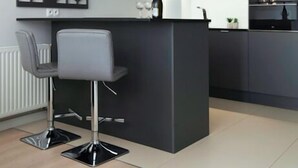 A modern kitchen with dark cabinetry, a central island, and a pendant light. - Elite Apartments Waterlane SPA (Gdansk)