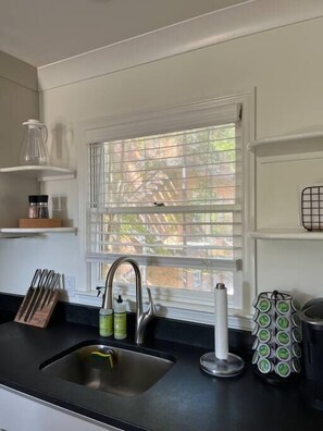 Kitchen area with stainless steel sink, knife block, and condiment bottles.