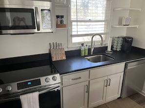 Enjoy cooking in this well-equipped kitchen with a black countertop, stainless steel appliances, and ample storage.
