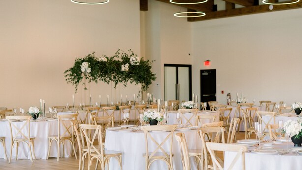 A banquet hall with round tables, wooden chairs, and white tablecloths. - Wilbur Mansion (Bethlehem)
